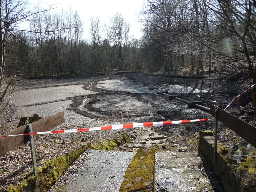 Das Wasser aus dem Überlaufbecken des Hölzersees ist abgelassen. Weil der Damm zwischen See und Becken nicht dicht ist, läuft ständig Wasser nach.    Bild: Reichert