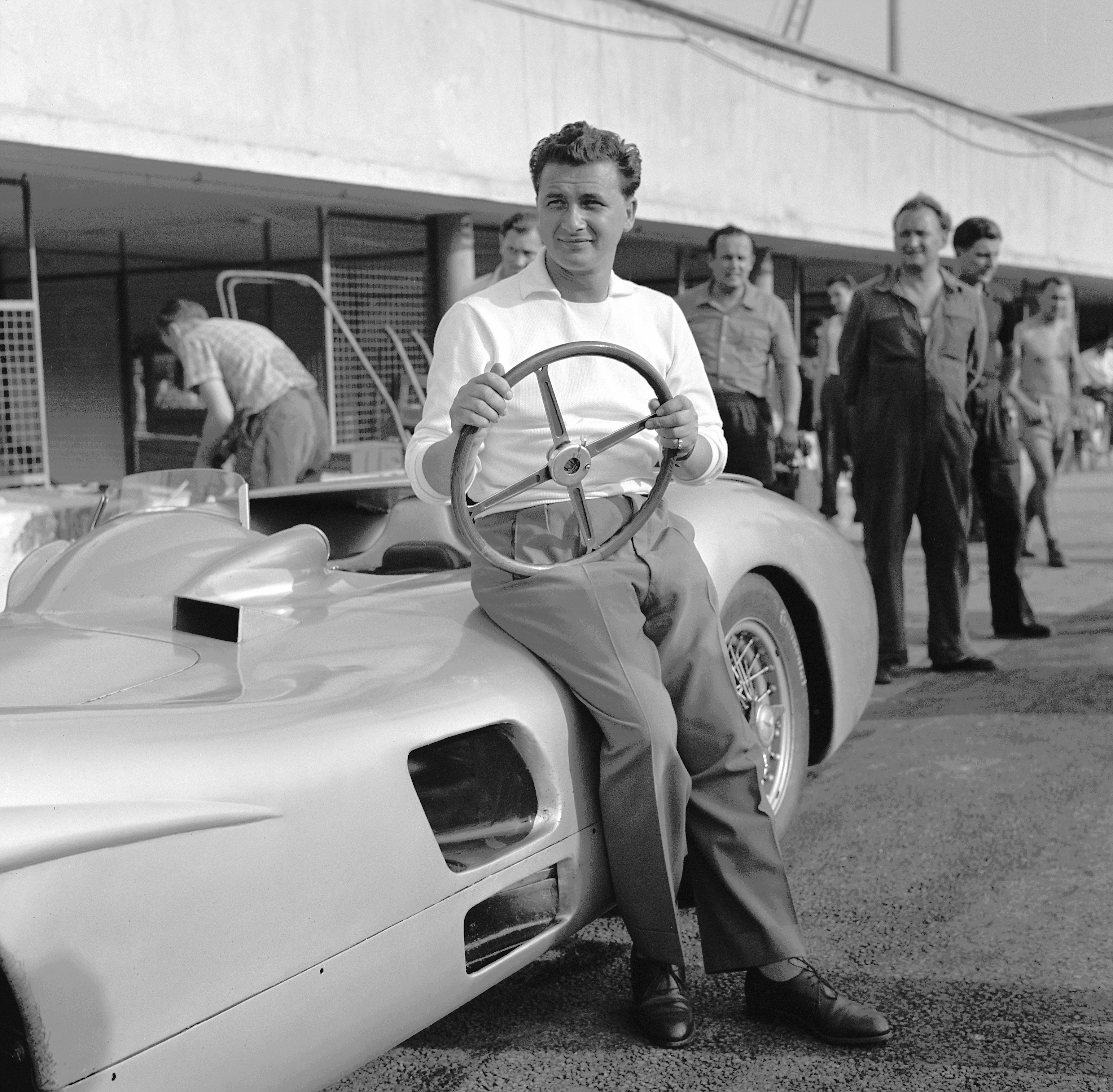 Mercedes-Benz Rennfahrer Hans Herrmann im August 1955 bei Versuchsfahrten auf dem Autodrom in Monza, neben dem Formel-1-Rennwagen W 196 R mit Stromlinienkarosserie. Bild: Mercede Benz Classic