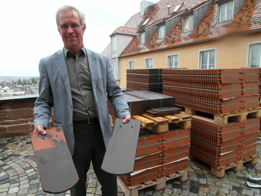 Dekan Bernd Liebndörfer zeigt die Dachziegel der Böblinger Stadtkirche: Links einer der 70 Jahre alten denkmalgeschützten Dachziegel, die wiederverwendet werden können - rechts einer der neuen Ersatz-Ziegel, deren rotbraune Farbe mit der Denkmalschutzbehörde abgestimmt werden musste.    Bild: Staber