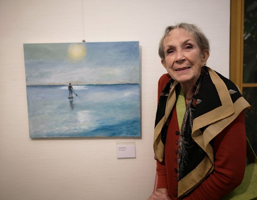 Karin Pröschild, von Anfang an, also seit 45 Jahren in der Gruppe, vor ihrem Bild "Die große Reise", inspiriert vom SZ/BZ-Foto zu Harald Kümmels 700 km langer Fahrt über die Elbe.   Bild: Schilpp