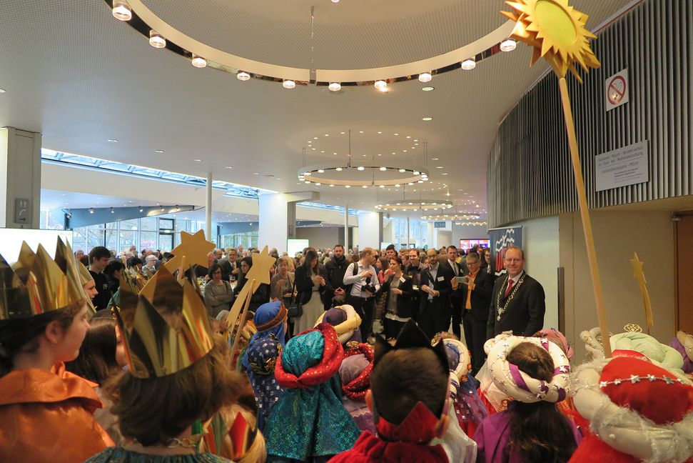 Die Sternsinger aus den Gemeinden St. Anna, St. Maria, St. Joseph und zur Heiligen Dreifaltigkeit empfangen OB Dr. Vöhringer und das Publikum im Foyer der Stadthalle (Bild: Groß).
