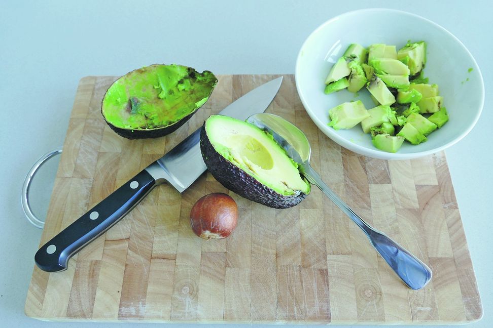 • Die Avocadohälfte mit dem Kern wieder auf die Schneidunterlage legen, Hände wegnehmen und nun mit der Messerschneide auf den Kern schlagen: Die Schneide bleibt im Kern stecken und er kann somit durch leichtes Drehen des Messers entfernt werden.
