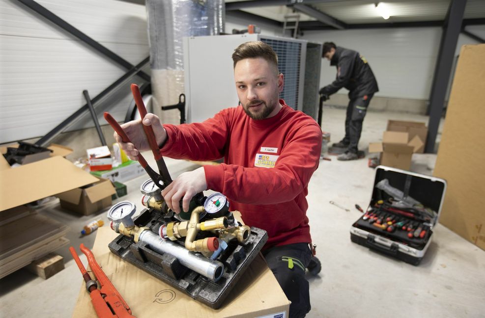 Ein Heizungsbauer montiert eine Wärmepumpe.