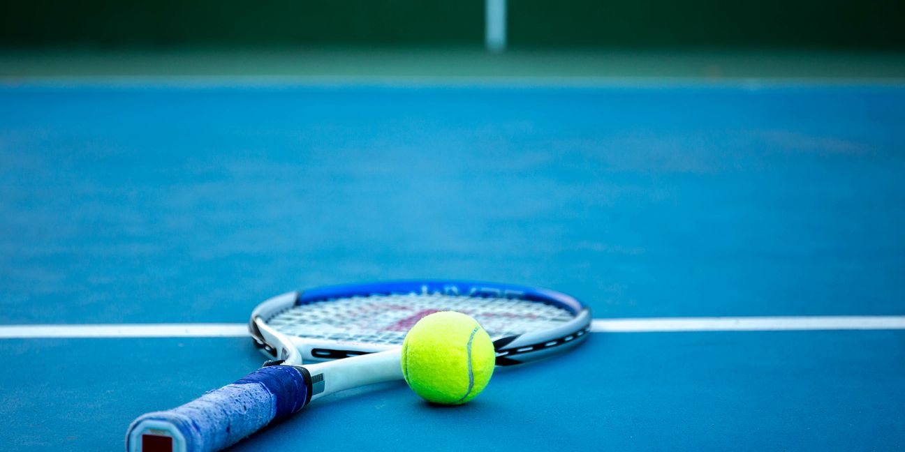 Tennis ball and racket on tennis court with white line