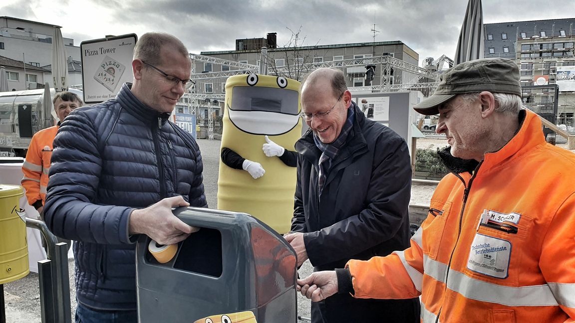 Grünamt-Leiter Ralf Bültge-Bohla, Oberbürgermeister Dr. Bernd Vöhringer und Martin Schindler von den Technischen Betriebsdiensten bringen den ersten Mülltoni 2.0 am Grünen Platz an (von links).     Bild: Wegner