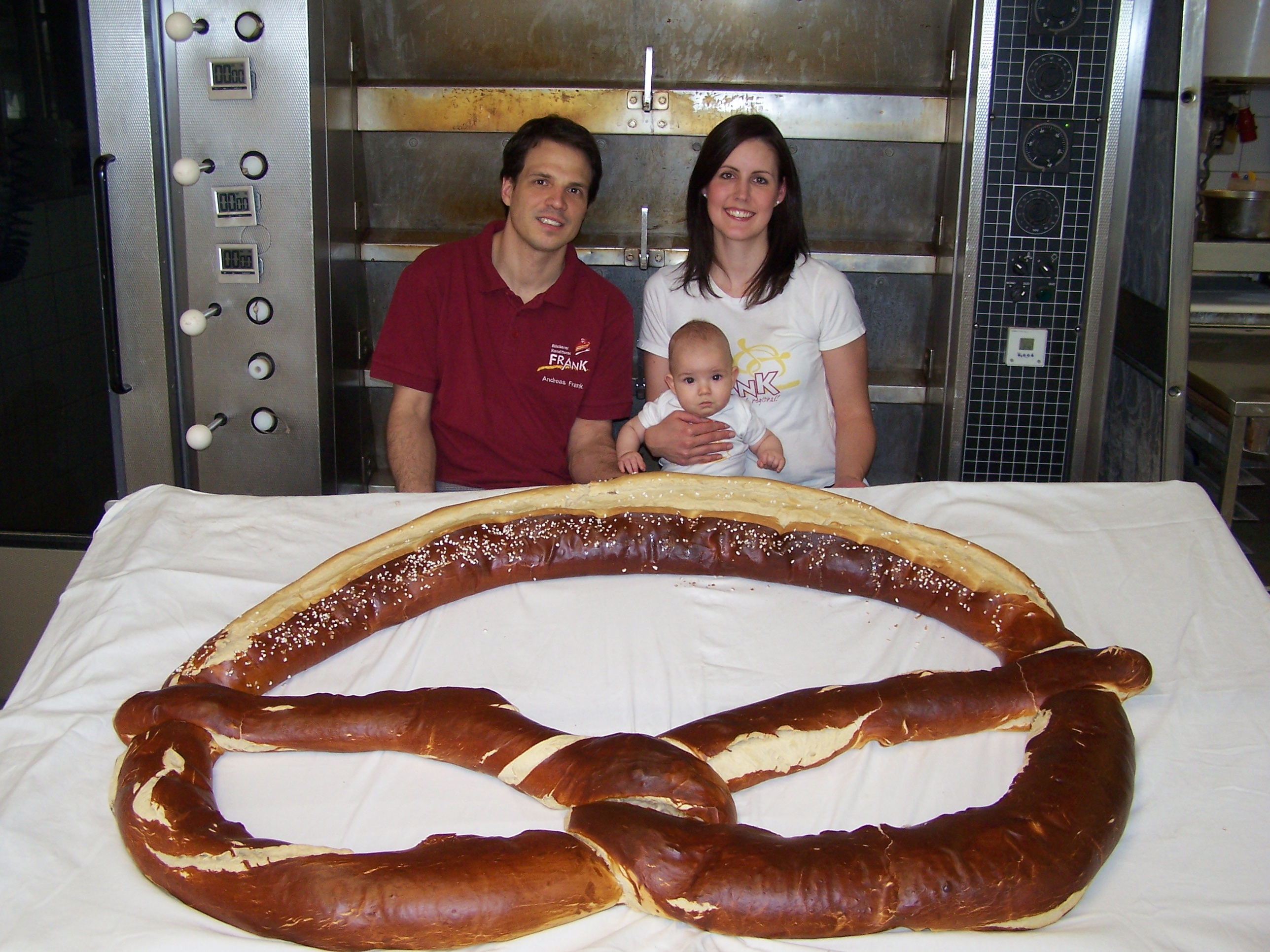Andreas und Stefanie Frank, hier mit Sohn Paul, sind von der Riesen-Brezel begeistert: Die Bäckerei Frank in Maichingen hat 20 Kilogramm Teig zu einer XXL-Brezel verarbeitet, die morgen bei der Aus- und Weiterbildungsmesse des Handwerks am Messestand der Bäcker-Innung ausgestellt wird. Bild: Rothacker