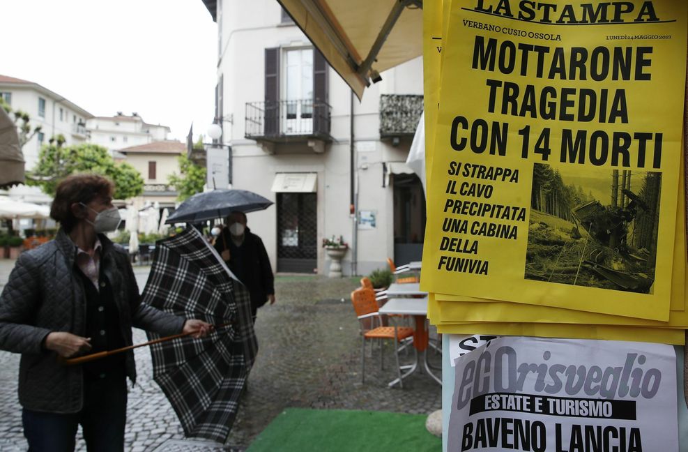 Menschen an einem Zeitungskiosk in Stresa, an dem eine Zeitung mit der Schlagzeile „Mottarone-Tragödie mit 14 Toten“ ausgehängt ist. Foto: dpa/Antonio Calanni