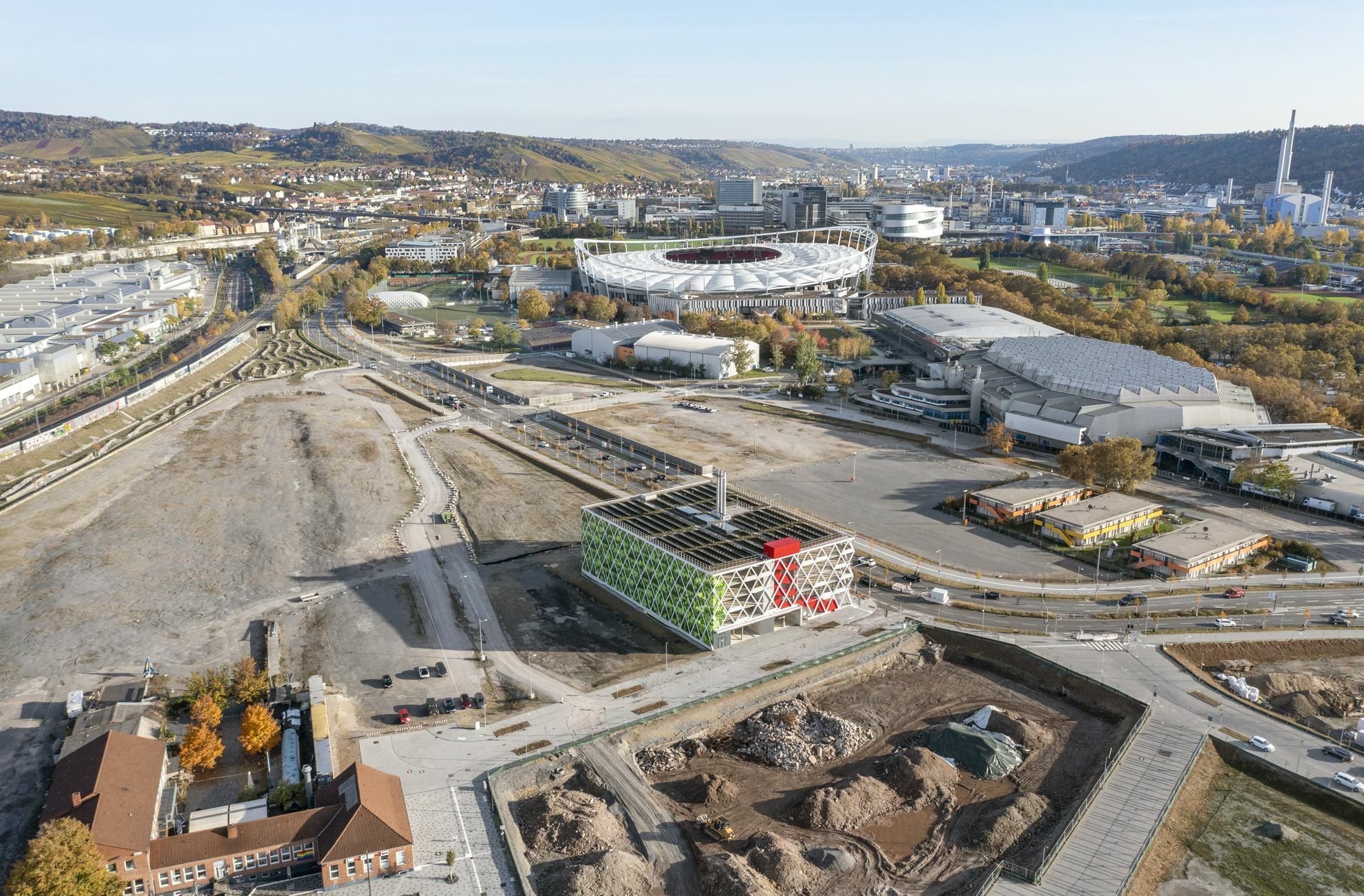 Noch herrscht drumherum Leere: das Quartiersparkhaus Q16 mit integrierter Energiezentrale im Neckarpark markiert prominent den Zugang zum neuen Quartier Neckarpark in Bad Cannstatt.  Am unteren linken Bildrand das Stadtarchiv Stuttgart, oben rechts sieht man Porschearena und Schleyerhalle, links davon die  Mercedes Benz  Arena.