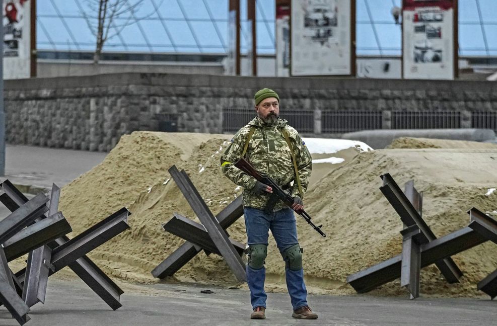 Ein bewaffneter Mann steht während eines Luftangriffsalarms auf dem Maidan-Platz neben einer Barrikade.
