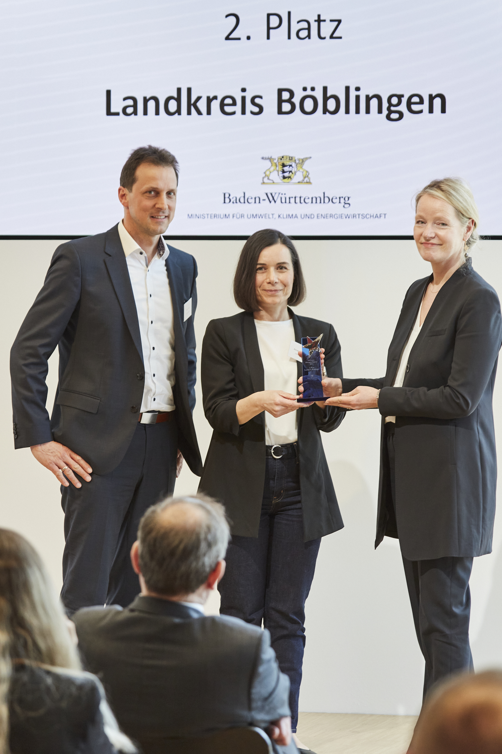 Umweltministerin Thekla Walker (rechts) übergibt den Preis an Klimaschutzmanagerin Anna-Lisa Morhinweg und den stellvertretenden Landrat Martin Wuttke. Bild: z