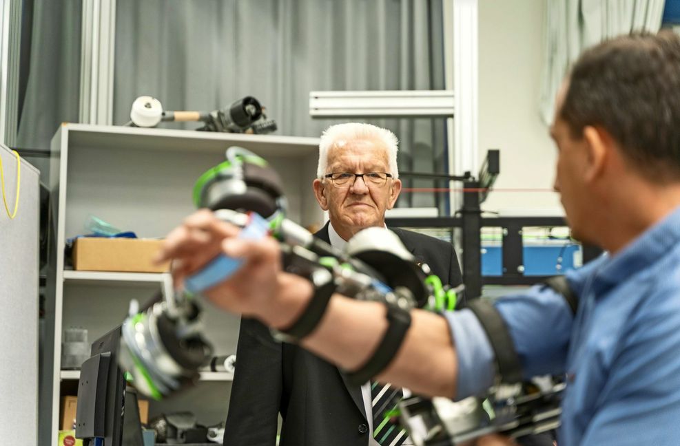 Winfried Kretschmann lässt sich  Assistenzsysteme für Schlaganfallpatienten vorführen.