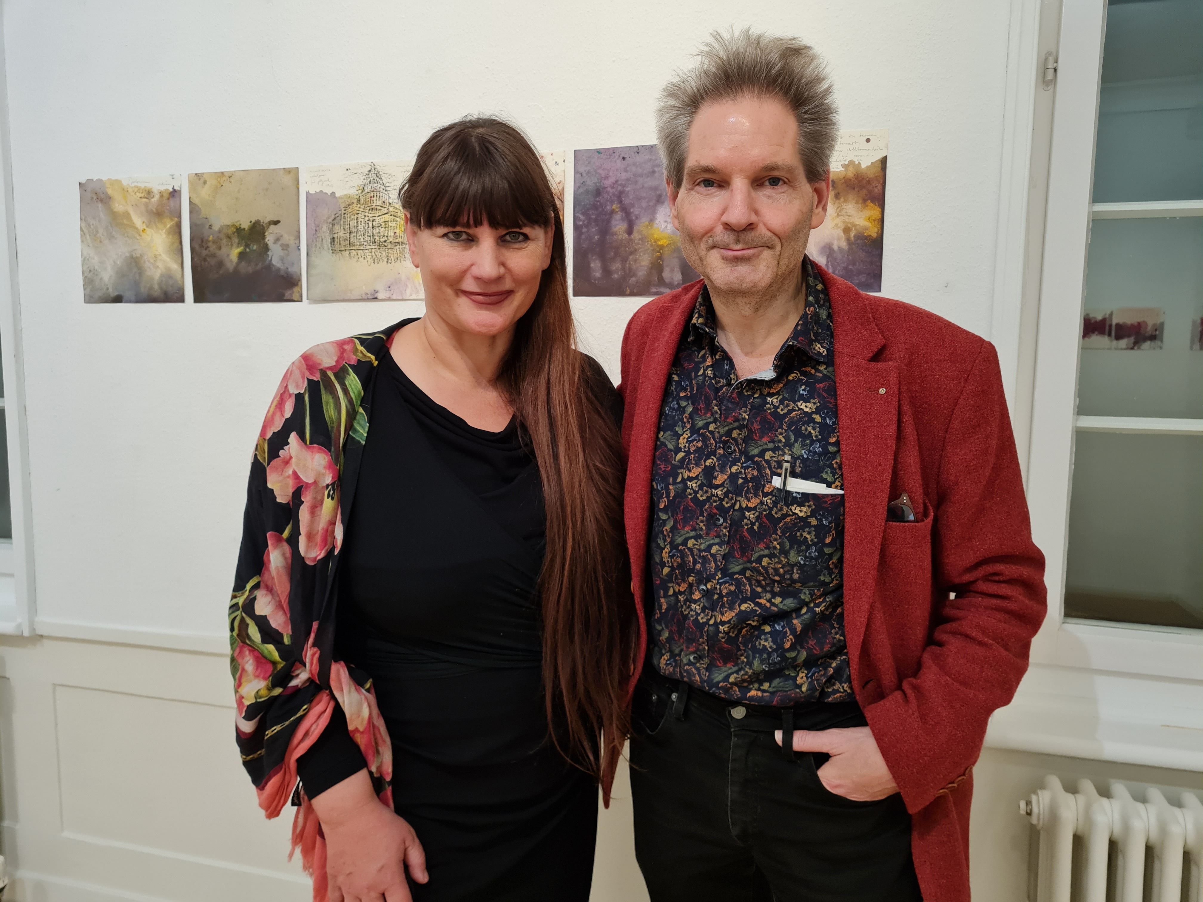 Die Stuttgarter Künstlerin Anette C. Halm mit Dr. Günter Baumann bei der Eröffnung der Doppelausstellung im Alten Amtsgericht. Im Hintergrund die Serie von Arbeiten zu Marie Curie.    Bild: Schilpp